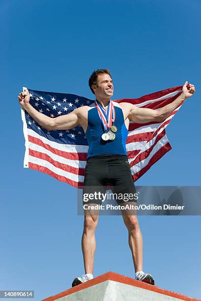 male athlete on winner's podium, holding up american flag - olympic podium stock pictures, royalty-free photos & images