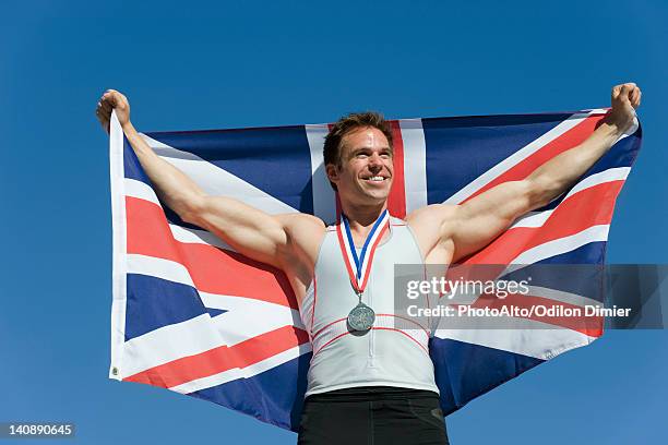 male athlete on winner's podium, holding up british flag - olympic podium stock pictures, royalty-free photos & images