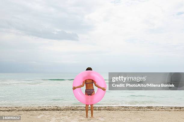 girl holding inflatable ring on beach, rear view - inflatable ring stock-fotos und bilder