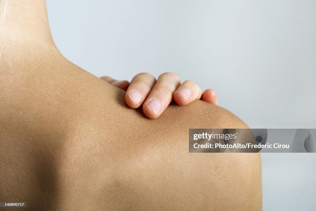 Woman with hand on bare shoulder, close-up