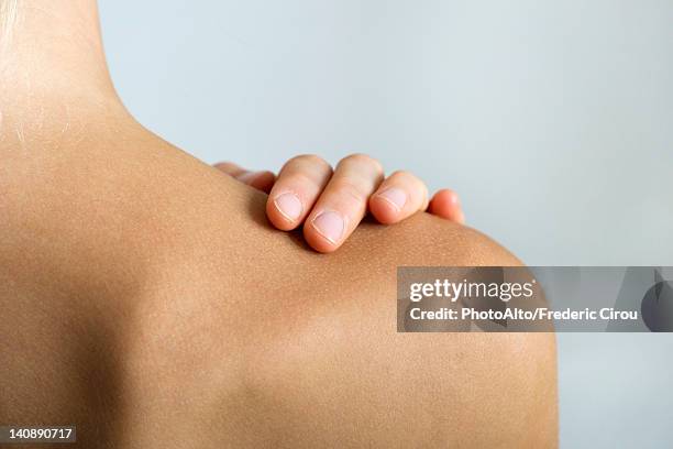 woman with hand on bare shoulder, close-up - schouder stockfoto's en -beelden