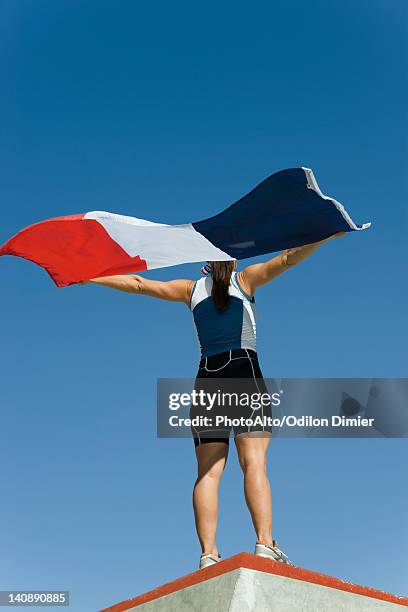 female athlete on winner's podium, holding up french flag - olympic podium stock pictures, royalty-free photos & images