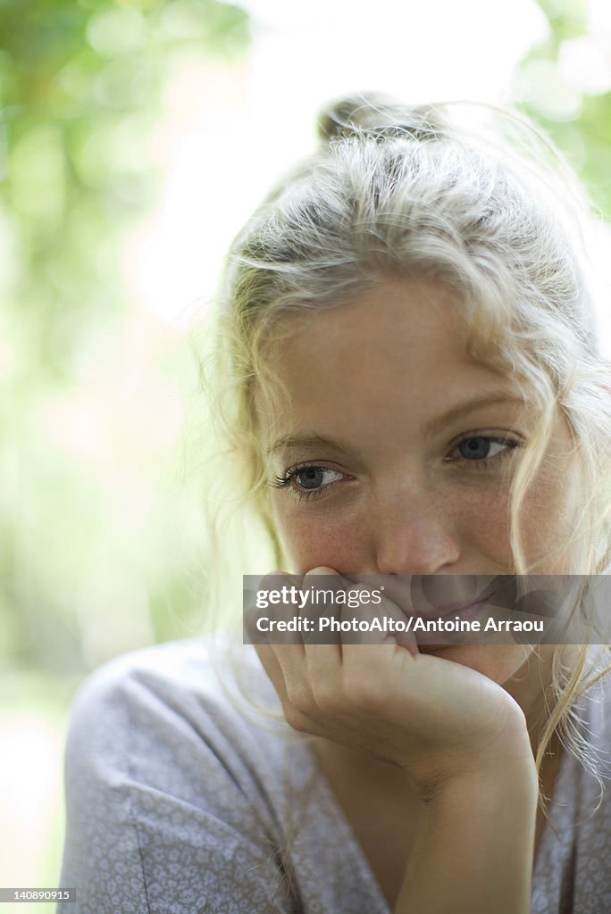 Woman with chin resting on hand, looking away in thought