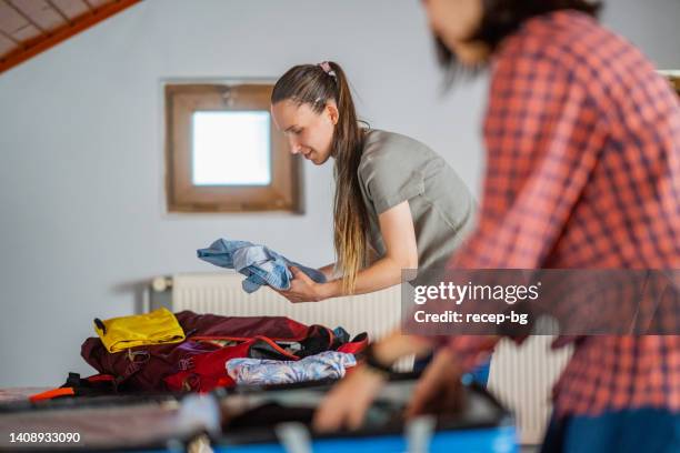 two multi-ethnic female tourists unpacking their luggage at their rental home for home-staying - hostel stock pictures, royalty-free photos & images