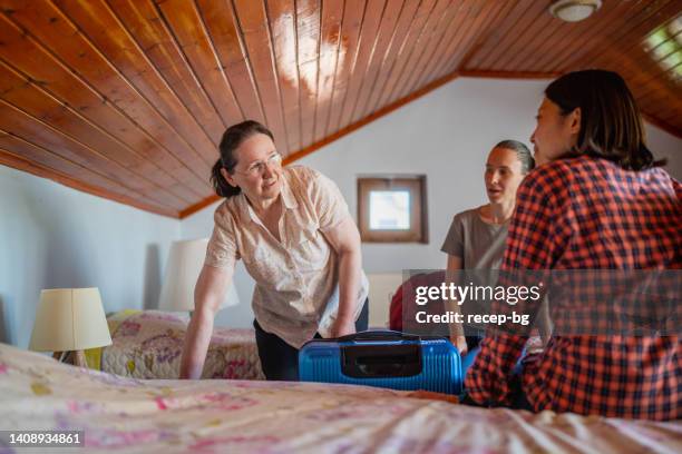 gastgeber-mutter, die zwei multiethnischen weiblichen touristengästen für den aufenthalt zu hause begrüßt und ihr das schlafzimmer zeigt - hostel room stock-fotos und bilder