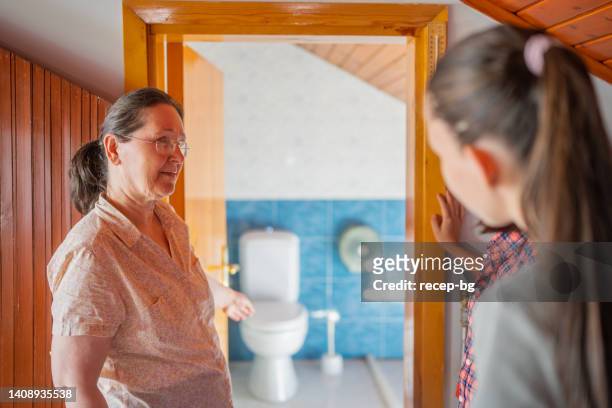host-mother welcoming and showing bed room and toilet and bathroom to two multi-ethnic female tourist guests for home-staying - staying in hotel stock pictures, royalty-free photos & images