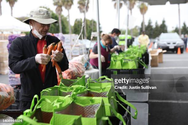 Volunteers pack bags of food during an Alameda County Community Food Bank food giveaway at Acts Full Gospel Church on July 15, 2022 in Oakland,...