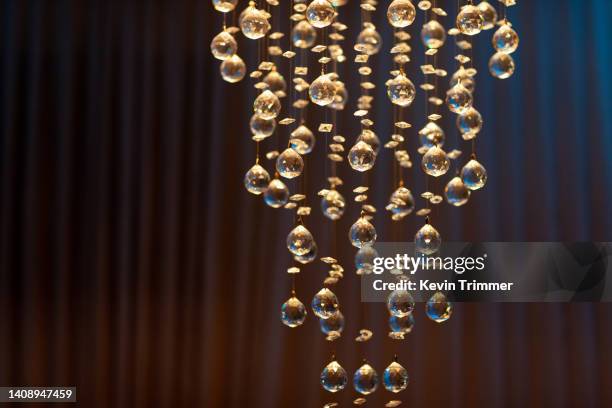 moody closeup of brightly lit crystal chandelier against a dark backdrop - hanging artwork stock pictures, royalty-free photos & images