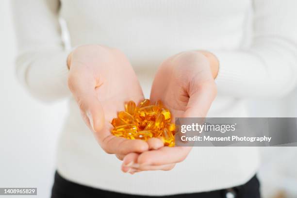 woman hands holding omega-3 pills close-up - vitamine d stockfoto's en -beelden