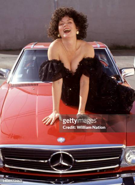 Model dressed in a cocktail/party dress from clothing store Cinema Glamour Shop, poses for a portrait on the hood of a Mercedes-Benz in 1992 in Los...