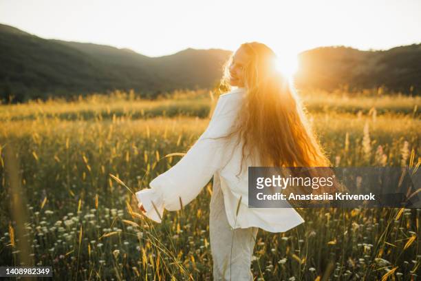 young girl with long hair is spinning in flowering field. - kamille stock-fotos und bilder