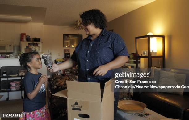 Amber Flame and her daughter, Evelia Taylor unpack their new vacuum that they received through the Reparations.me website, at their Concord, Calif.,...