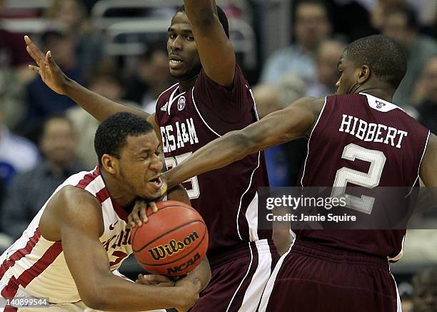 Steven Pledger of the Oklahoma Sooners is fouled by Ray Turner and Naji Hibbert of the Texas A&M Aggies during the first round of the Big 12...