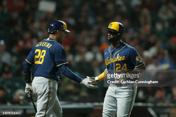 Andrew McCutchen of the Milwaukee Brewers celebrates with Pedro Severino after scoring from third base on a walk by pitcher Tyler Rogers of the San...