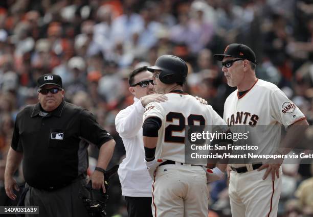 Buster Posey is checked out by Dave Groeschner and Manager Bruce Bochy after he was hit in the head by a pitch as the San Francisco Giants played the...