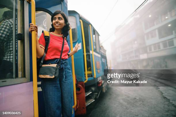 woman standing at a moving train door - india train stock-fotos und bilder