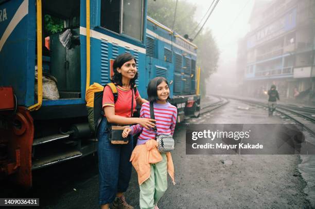 mother and daughter standing near a tourist train - bengali girl stock-fotos und bilder