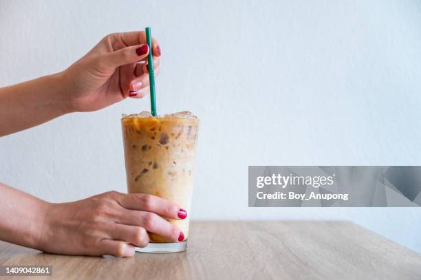 someone hand holding a straw before drinking iced milk coffee. - iced coffee stockfoto's en -beelden