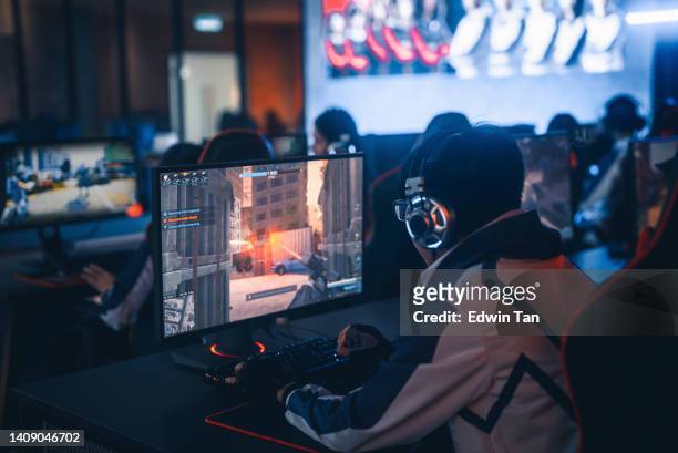 rear view asian chinese esports team gamer focus playing rpg first shooter game in grand final sport event championship arena. cyber games tournament event - multiple screens stockfoto's en -beelden