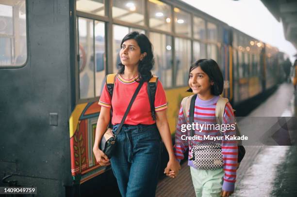mother and daughter walking at a train station platform while a train is halted at the platform - bengali girl stock-fotos und bilder