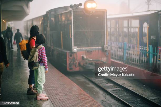 mother and daughter waiting at a train station platform - bengali girl stock-fotos und bilder