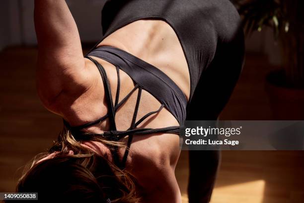 athletic female in yoga twist in a sunny yoga studio - show of strength stock-fotos und bilder