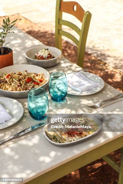 greek dinner table with food and plates under olive trees with cretan delicacies - cultura grega imagens e fotografias de stock
