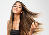 Brown Hair Beauty Woman. Brunette Model with Shiny Straight Long Hairstyle. Hair Care Spa and Keratin Straightening over White. Cheerful Smiling Girl touching flying Healthy Smooth Hair