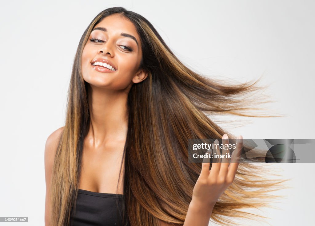 Brown Hair Beauty Woman. Brunette Model with Shiny Straight Long Hairstyle. Hair Care Spa and Keratin Straightening over White. Cheerful Smiling Girl touching flying Healthy Smooth Hair