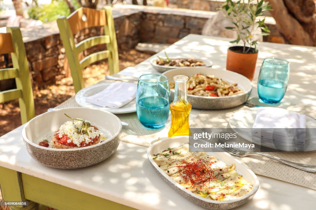 Greek Dinner Table with Food and Plates under olive trees with Cretan delicacies