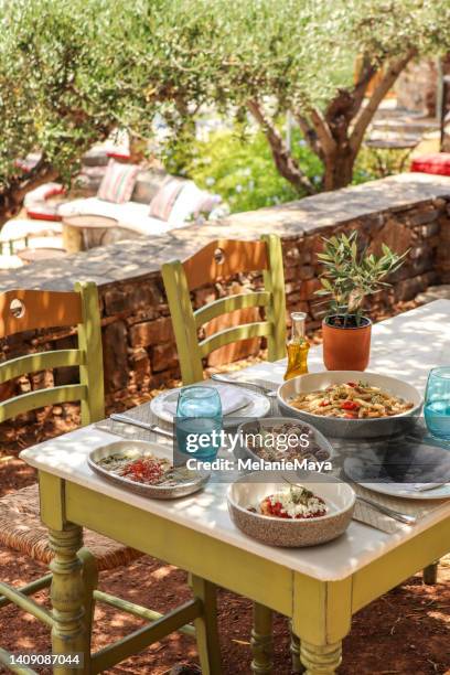 table à manger grecque avec nourriture et assiettes sous les oliviers avec des délices crétois - crète photos et images de collection