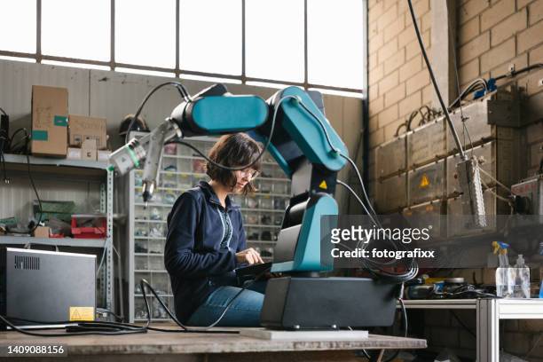 female technician programs a robot arm with a digital tablet - computer aided manufacturing stock pictures, royalty-free photos & images