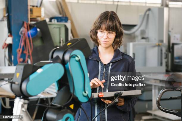 technikerin programmiert einen roboterarm mit digitalem tablet - berufsausbildung stock-fotos und bilder