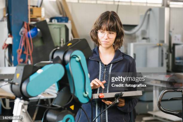 female technician programs a robot arm with a digital tablet - trainee program stock pictures, royalty-free photos & images
