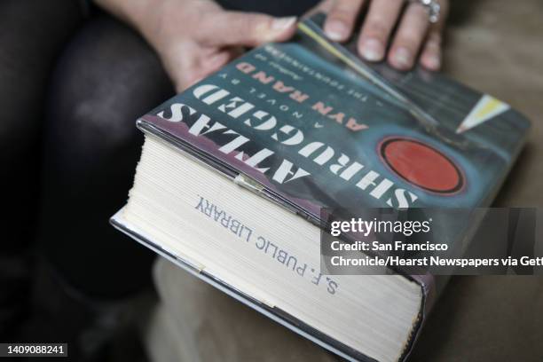 Joanne Hall holds a first edition copy of Atlas Shrugged by Ayn Rand she borrowed in 1983 from the San Francisco Public Library in her home in...