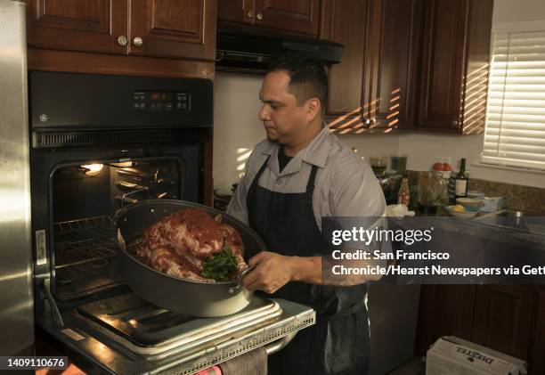 Jonnatan Leiva places the turkey in the oven as he and his mom Anna Leiva prepare a family recipe of drunken turkey, or Pavo Borracho, in his...