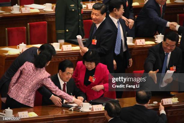 China's President Hu Jintao signs autographs for female delegates as Chinese Vice President Xi Jinping looks behind them after the second plenary...