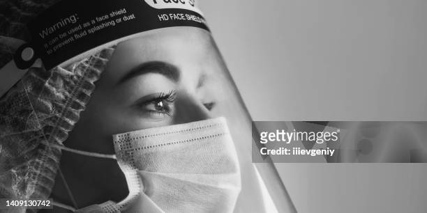 young doctor portrait in white coat and protective mask on gray background. black and white photography. medical specialist in professional uniform. face shield. protective gear. confident nurse - health shield stock pictures, royalty-free photos & images