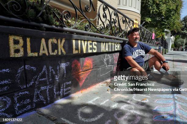 James Juanillo sits on the sidewalk outside his home which has been covered in supportive chalk art in San Francisco, Calif., on Monday, June 15,...