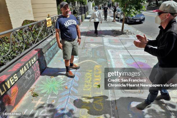 James Juanillo gets a little applause form a passerby on the sidewalk outside the home which has been covered in supportive chalk art in San...