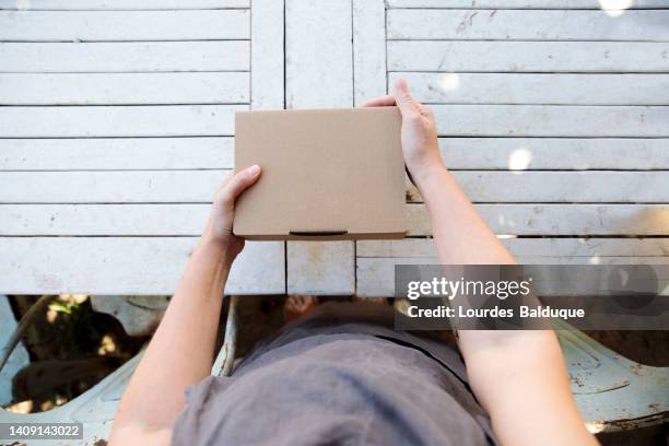 hands holding a cardboard package before sending it to a customer, view from above ( - woman hold box imagens e fotografias de stock