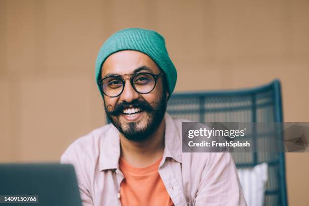 a handsome bearded businessman smiling while looking at camera - sikhisme stockfoto's en -beelden