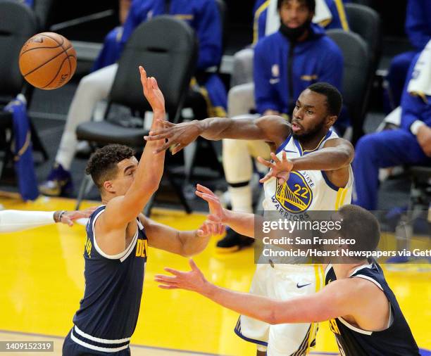 Andrw Wiggins passes to a teammate between Michael Porter, Jr., and Nikola Jokic during the first half as the Golden State Warriors played the Denver...