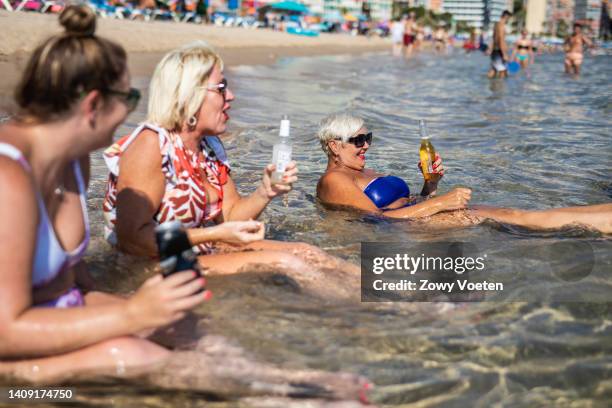 English tourists quench the heat by drinking in the sea at Levante beach as a heatwave sweeps across Spain on July 16, 2022 in Benidorm, Spain.