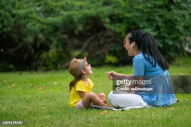 foto de madre e hija sentadas en pastos verdes y jugando juegos de manos - kinder muster fotografías e imágenes de stock