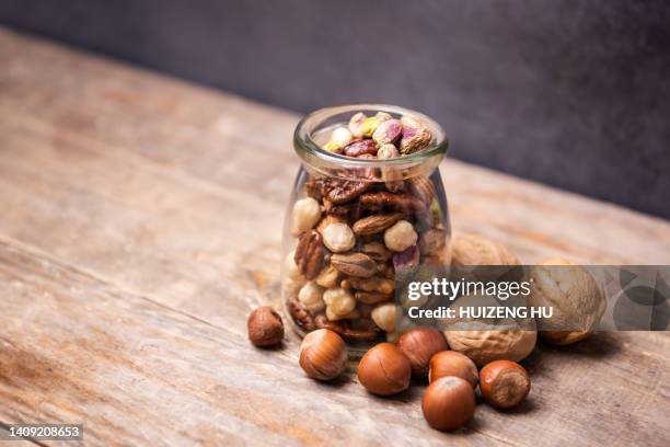 glass jar filled with a variety of nutrition and healthy nuts. pistachios, almonds, walnuts, hazelnuts, cashews - hazelnut meal stockfoto's en -beelden