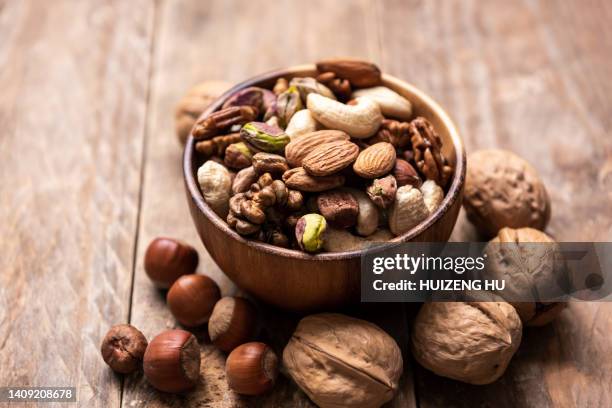 wooden bowl with mixed nuts on white table. healthy food and snack - pine nut stock pictures, royalty-free photos & images