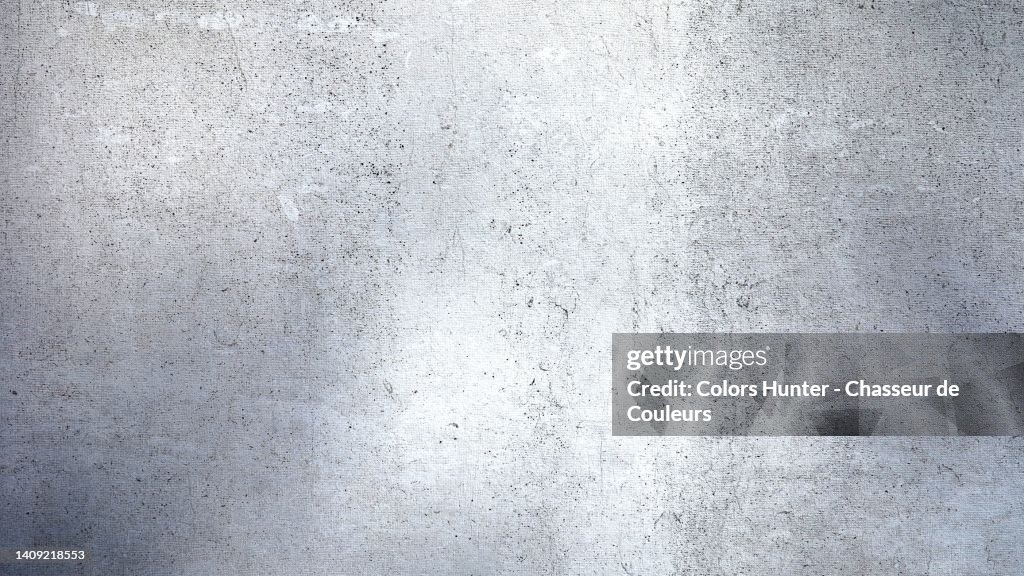 Textured cement wall, painted white and weathered in shades of gray in Paris, France