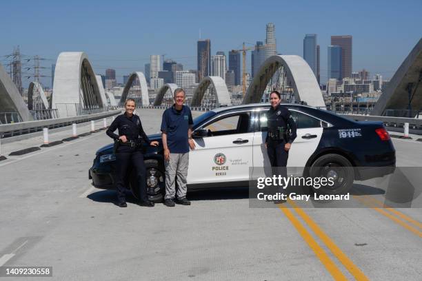 With the downtown skyline behind him City Engineer Gary Lee Moore poses for a portrait with two police women in front of their police car during the...