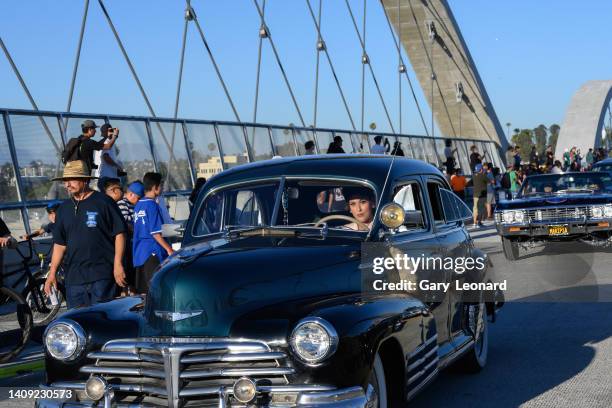 Striking woman drives a 1940s deep green Chevrolet across the bridge as part of a low-rider event during the opening of the new 6th Street Bridge on...